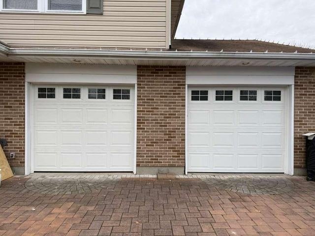 Two garage doors with windows on a brick home